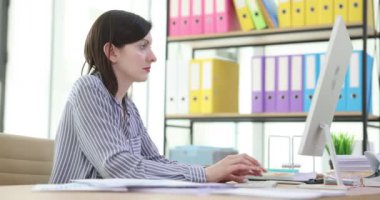 Attentive female employee works on a computer with documents. Manager secretary enters analytical data on the computer