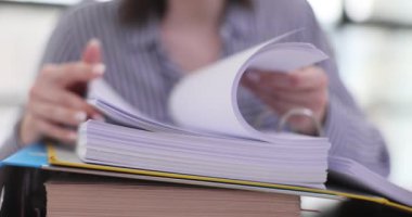 Woman quickly flips through stack of documents at workplace. Finding required document in folder in office