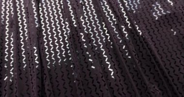 Closeup of dark purple fabric with geometric pattern of small light purple interlocking diamonds. Beautiful black fabric with patterns