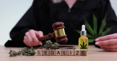 Yargıç marijuana yağı ellerinde, mahkeme salonunda tokmağı vuruyor. Marihuana yaprakları ve yargıç tokmak ve marihuana yasallaştırma kavramı