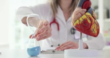 Kalp hastalığı teşhisi ve zaman kontrolü. Kardiyolog kum saati ve kalp anatomisini inceledi.