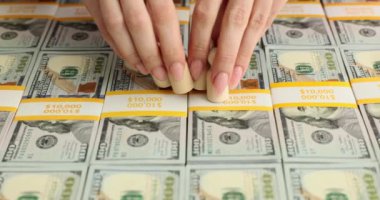 Yüz dolarlık banknotların arka planında yaşayan ahşap bir aile. Toplumun paraya bağımlılığı