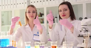 Laboratuvarda iki bilim adamı onay veriyor ve ellerinde test tüpleri var. Başarılı bilimsel deney onaylandı