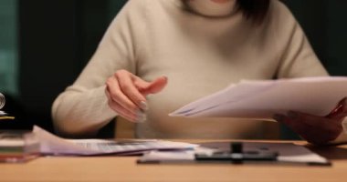 Bayan muhasebeci, gece geç saatlerde masada oturup belgelere göz atar. İş belgelerinin fazla mesai ve gözden geçirilmesi