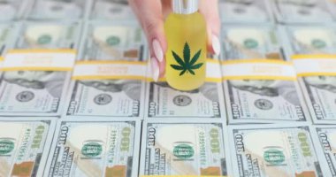 Yeşil kenevir yaprağı ve yüz dolarlık banknotlarla bir şişe CBD yağı. Marihuana yatırımı