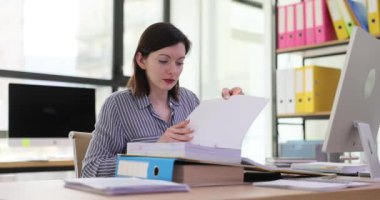 Ofis çalışanı kadın masadaki belgelere bakıyor. Yönetici iş belgelerini inceliyor