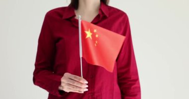 Çinli kadın gri arka planda Çin bayrağı taşıyor. Bayan, Çin kimliğini ve tarihini temsil eden sembol ve değerleri onurlandırıyor.