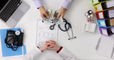 Erkek hasta özel klinikteki masada oturan banknotları yavaşça sayıyor. Sabırsız sağlık hizmeti sağlayıcısı olaya dahil oldu ve aceleyle parayı aldı