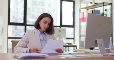 Kadın ofis çalışanı belgelerin içeriğini analiz eder. Profesyonel sekreter yavaş çekim onaylı kağıtları imzalıyor.