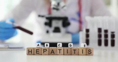 Doktor farklı hepatit türleri için kanı analiz eder. Tahta küpler, çeşitli karaciğer hastalıklarını gösteren HEPATITIS kelimelerini oluşturur.