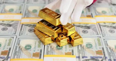 İşçi, minyatür altın külçelerini dolar destelerinin üzerine koyuyor. Çalışanlar, zengin şirketlerin varlıklarını çeşitlendirmeye kararlı olduklarını gösterdiler.