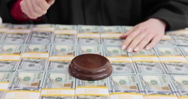 Kadın yargıç para yığınları hakkında karar vermek için tokmağı vurdu. Kadın, mahkemedeki mali sonuçların önemini vurguladı