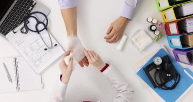 Doktor, hastane ziyareti sırasında erkek hastayı bandajla sarıyor. Doktor randevu sırasında etkili bir tedavi sunar