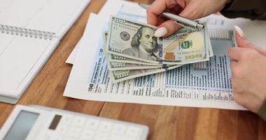Çalışanlar, şirketin işyerindeki IRS formuna dolar basıyorlar. Kadın vergi belgelerini doldurup gelir ve gider bildiriyor