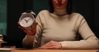 Şirket çalışanı, işyerinde yavaş çekimde klasik çalar saat gösteriyor. Yorgun kadın, iş-yaşam dengesi arayışında günün sonunda gösteri yapıyor