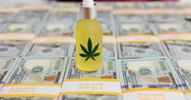 Amerikan dolarlarının üzerine yerleştirilmiş bir şişe kenevir yağı. Esrar pazarında tüketimin ve ticaretin görsel temsili