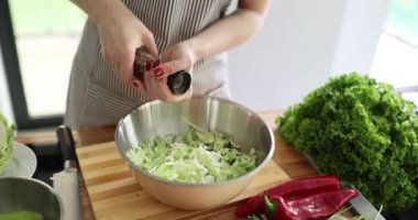 Genç ev hanımı doğranmış lahanaya aromatik baharatlar ekler. Kadın şef lezzetli ve besleyici sebze salatasını yavaş çekimde hazırlıyor.