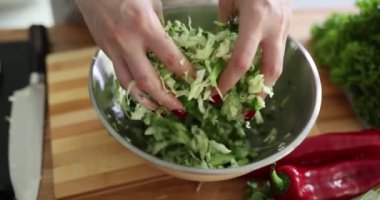 Genç bayan aşçı, doğranmış lahana ve salatalık karışımı yapar. Ev hanımı besleyici salata yapmak için çeşitli organik sebzeler kullanır.