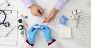Doktor, erkek hastanın parmağını sıkar. Laboratuvarda test için kan akışını teşvik eder. Eldivenli kadın doktor, avuç içi parmak yüzeyi mızraklıyor.