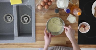 Kadın mutfağı ağır çekimde çırpıcı kullanarak malzemeyi kırbaçlıyor. Önlüklü ev hanımı kahvaltıda omlet pişirir.
