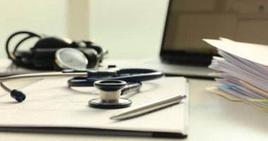 Klinikteki günlük idari işlerin organize kaosu üzerine steteskop. Tıbbi kayıtlar, hasta sağlığını takip etmek için devam eden çabaların fotoğrafını veriyor.