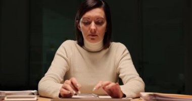 Şirket çalışanı işyerinde klavyede yazarken yorgun görünüyor. Yorgun kadın yönetici akşam ağır çekimde ofiste rapor hazırlıyor.