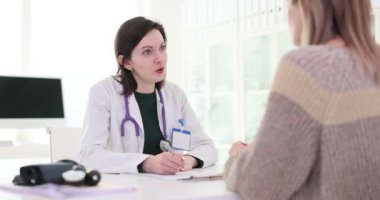 Steteskoplu bir doktor hastanedeki bayan hastayı dinliyor. Kadın yetenekli bir terapistten yardım isteyen bir hastalıktan bahsediyor.