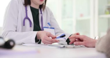 Aile doktoru randevuda kadının parmağına nabız ölçer takıyor. Steteskoplu kadın terapist hastanın oksijen durumunu değerlendiriyor.