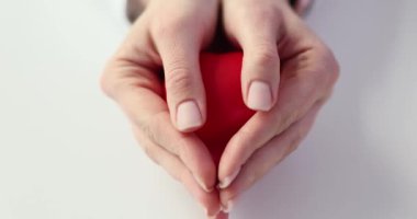 Kadın, oyuncak kalbini beyaz arka planda yavaş çekimde göstererek ellerini açar. Etkili tedavi için sağlık hizmeti sağlayıcısına duyulan güven kavramı