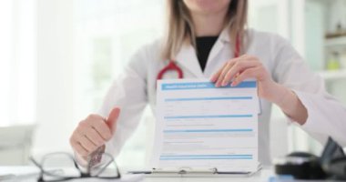 Kadın doktor, hastanedeki iş yerinde sağlık sigortası poliçesi ve onayı gösteriyor. Pozitif kadın doktor hastaya şeffaf işbirliği teklif ediyor