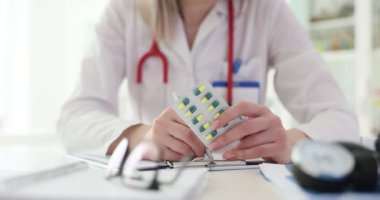 Kadın doktor tedavi için gerekli hapları yazıyor. Doktor ilaç için detaylı reçete yazıyor ve dozajı yavaş çekimde açıklıyor.