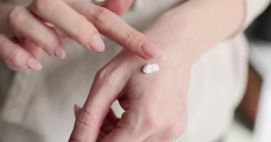 Genç bayan az miktarda nemlendirici kremi dikkatle sürüyor. Dişi, alerjik reaksiyonu kontrol etmek için cildine krem sürer. Yavaş çekim.