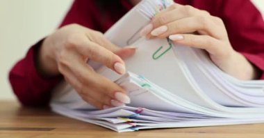Genç bayan sekreter büyük kağıt yığınını inceler. Ofis çalışanı gerekli bilgileri arayan belgelerin içeriğini inceliyor