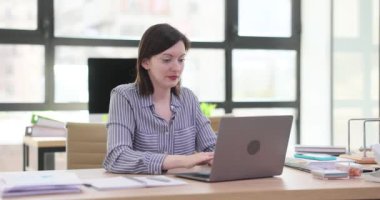 Dizüstü bilgisayarda çalışan kadın ofis çalışanı tipli, odaklanmış bakışları ağır çekimde. Kadın bilgisayarını kapattı. Kollarını başının üstüne uzattı. Geriye doğru yoğurdu.