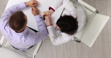 Doktor, klinikte otoskop kullanan erkek hastaları muayene ediyor. Kadın terapist randevuda kulak kanalını tıbbi aletlerle dikkatlice inceler.