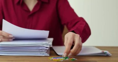 Şirket çalışanı işyerindeki mali raporlara ataç takıyor. Kadın çalışan, kağıtları düzenlemek için monoton işler yapıyor.