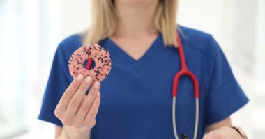 Beslenme uzmanları klinikte çörek ve mezura gösteriyor. Doktor kalori alımı ve egzersizi tartışıyor.