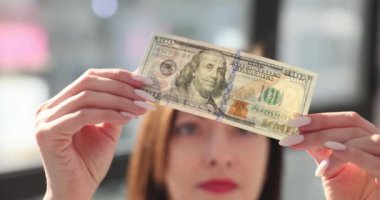 Sahte parayı kontrol ediyorum. Kadın elinde 100 dolar. Para kazanma ve para kazanma arayışı