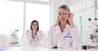 Laboratuvarda çalışan kimyager ya da doktor cam şişe getirip kameraya bakıyor. Laboratuvarda bilimsel tıbbi araştırma