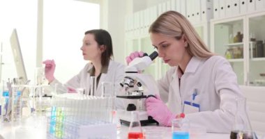 Tıbbi gelişim laboratuarındaki bilim adamları mikroskop altında bir örneği inceliyorlar. Laboratuvar asistanı kimyagerler bilimsel laboratuvarda araştırma yapıyorlar.