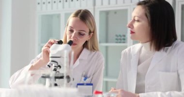 İki kimyager doktor laboratuvarda projeyi tartışıyor ve mikroskopla inceliyorlar. Bilimsel tıp laboratuarındaki laboratuar asistanlarının takım çalışması