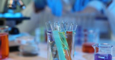 Bilim adamı laboratuardaki test tüplerinde renkli zehirli sıvılarla çalışıyor. Test tüplerindeki bilimsel özellikler ve kimyasal reaksiyonlar