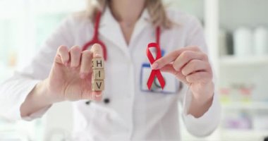 Doktor elinde kırmızı kurdele ve ahşap bloklar tutuyor. HIV görüldü, semptomlar ve önleme