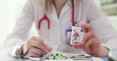 Doktor elinde ilaç şişesiyle reçete yazıyor. Reçete yazma prosedürü