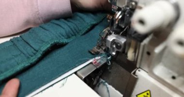 Dikiş makinesinde yeşil kumaş üzerinde çalışan terzi. Terzi stüdyosu
