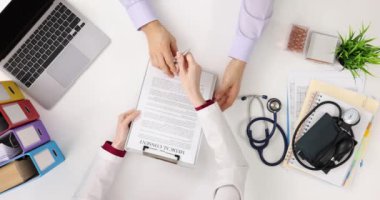 Doktor ofisinin üst görüşünde bilgilendirilmiş imzaları inceleyen bir adam. Hastanın tıbbi müdahaleye rızası