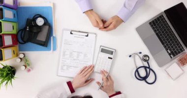 Doktor, hasta muayene masrafları için hesap makinesi düşünüyor. Sağlık hizmetleri veya sağlık sigortası maliyetleri