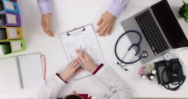 Doktor ve hasta tıbbi formları tartışıyor ve üst görüşü tartışıyorlar. Hasta tıbbi kayıtlarını dolduruyorum.