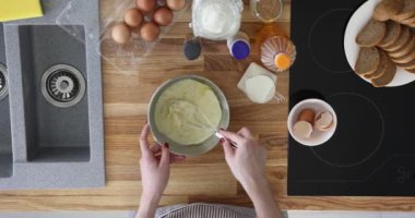 Sade ve lezzetli bir omlet ya da gözleme hazırla. Elle hamur yoğuran bir kadın çırpıcılı bir kâse içinde ve mutfakta pişirmek için adım hazırlıyor.