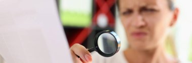 Gazete okumaya çalışan kadın portresi büyüteçle, daha net görebilmek için şaşı bakıyor. Görme sorunları nedeniyle metni görmekte zorlanan kadın